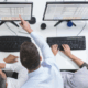 People working on workstations pointing at the screen